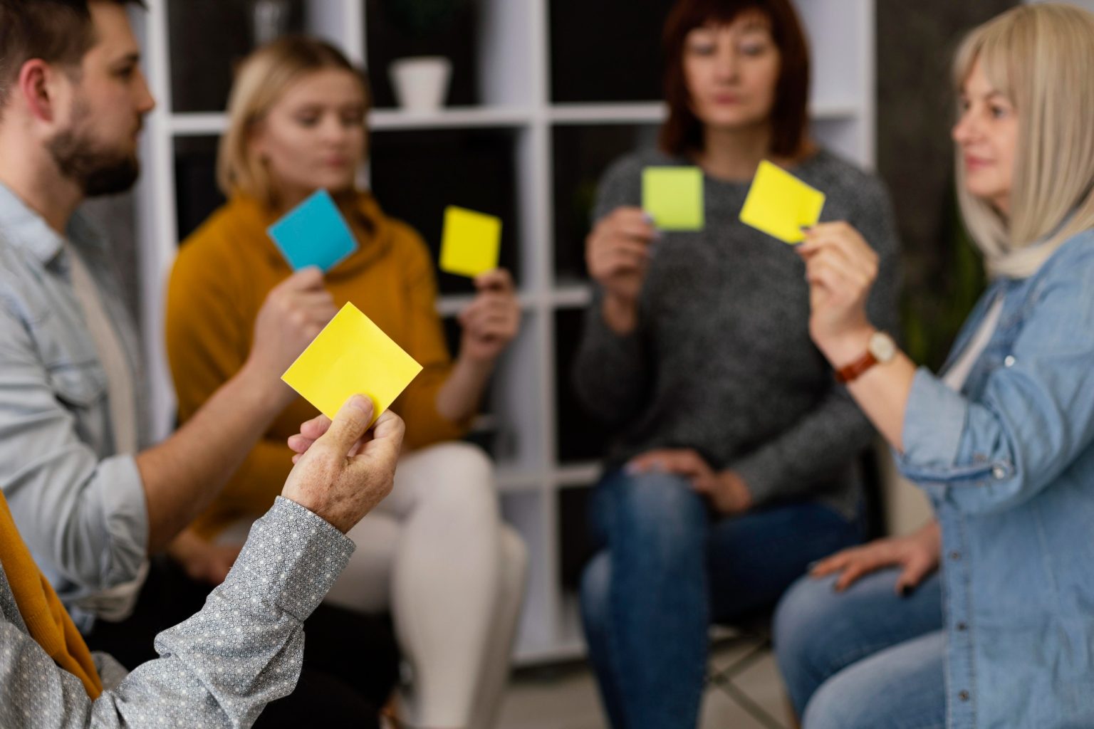 quipo en un taller de comunicación con facilitadora guiando una dinámica con notas adhesivas.